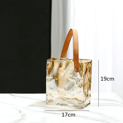 Transparent gold-tinged clear glass bucket bag with tan leather handle featured as decorbites clear glass vase decor