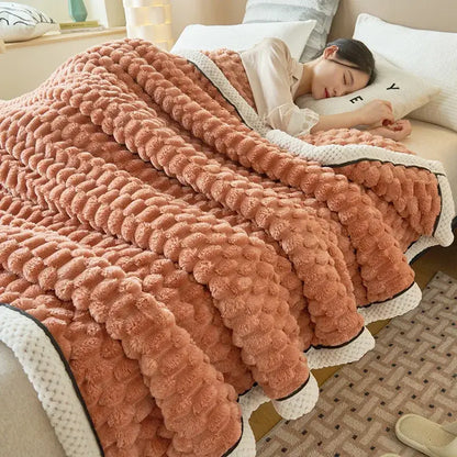 A cozy peach coral fleece warm blanket with raised pom-pom texture and contrasting white knit decorbites coral fleece trim