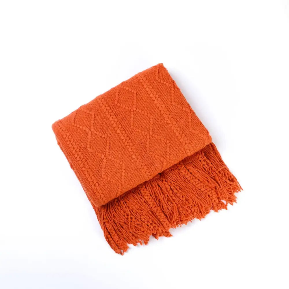 A cozy knit throw blanket in orange with textured diamond pattern and fringed edges for living room decorbites cozy knit