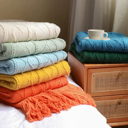 Stack of colorful textured diamond knit throw blankets in cream light blue yellow orange and teal for cozy knit decorbites