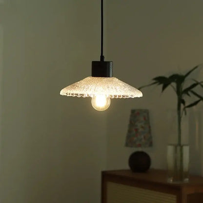 A warm glowing pendant light with a textured frosted clear glass shade and black metal fixture for kitchen decorbites clear glass LED lighting