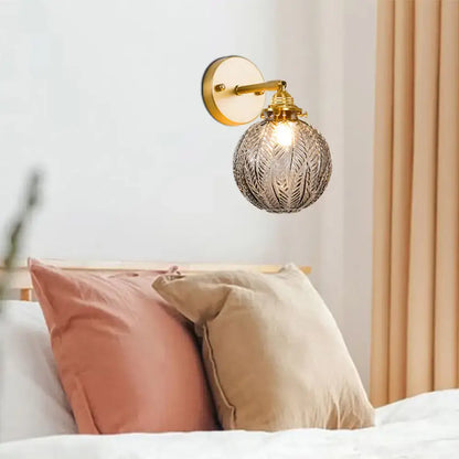 Textured glass ball wall light with etched spherical glass and gold-toned metal fixture for bedroom sconce lighting