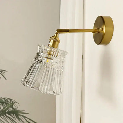 Textured glass brass mirror wall sconce featuring a clear fluted glass lampshade with a brass-finished metal arm for decorbites brass mirror