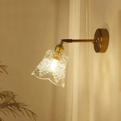A clear glass lampshade with floral etchings mounted on a brass mirror wall sconce for bedroom decorbites brass mirror