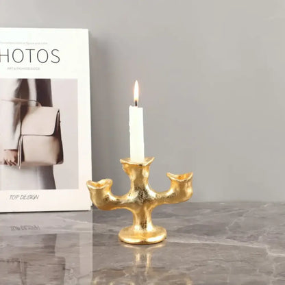 Gold-colored textured resin candle holder from decorbites holding a single white candle for dining room centerpiece