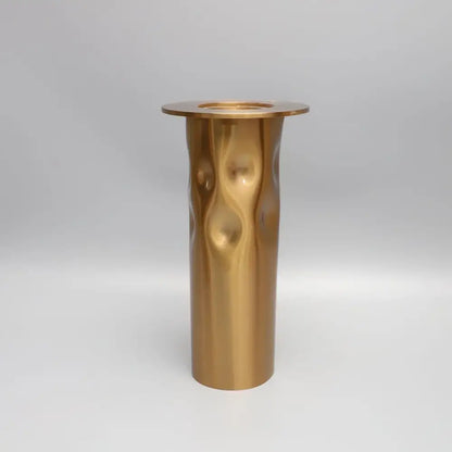 A sleek gold-toned metal candlestick holder with hammered texture and flat rim from decorbites golden metal set