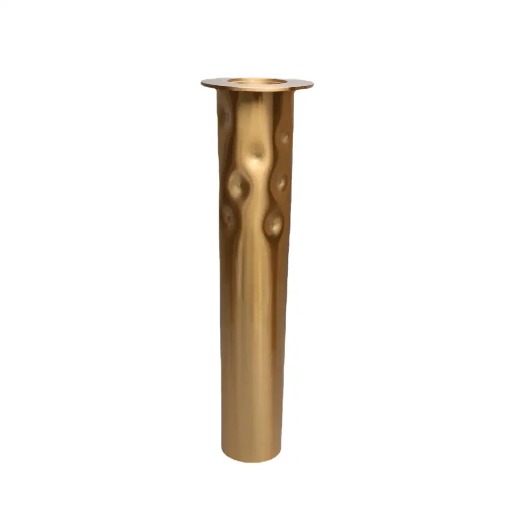 A tall slender brass golden metal candlestick holder with hammered texture and circular indentations for dining room decorbites