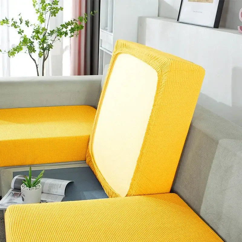 Bright yellow knitted sofa cover with textured elastic fabric snugly fitting back and seat cushions for living room use