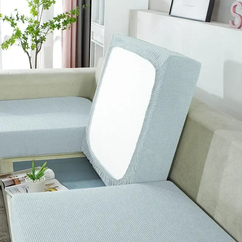 Light blue textured fabric sofa cover with elasticized edges and snug fit over backrest for furniture protection