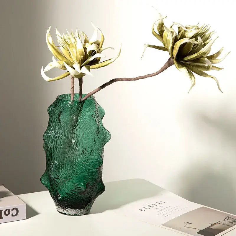 Textured green sea cucumber glass vase with sculpted organic form holding gold and olive artificial flowers for living room decor