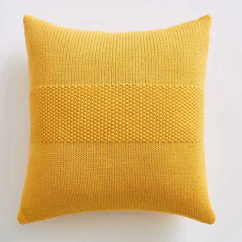 A square mustard-yellow knitted throw pillow with textured knit cushion cover and two horizontal denser stitch bands