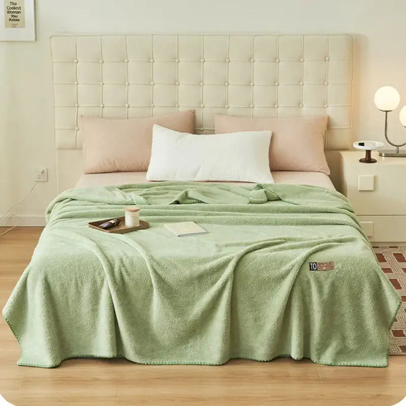 A soft mint green plush decorbites cloud comforter throw blanket with textured surface and embroidered logo corner