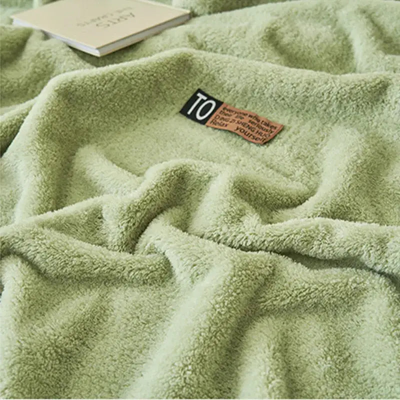 A soft moss green textured decorbites cloud comforter plush blanket with a cozy surface and stitched label near corner