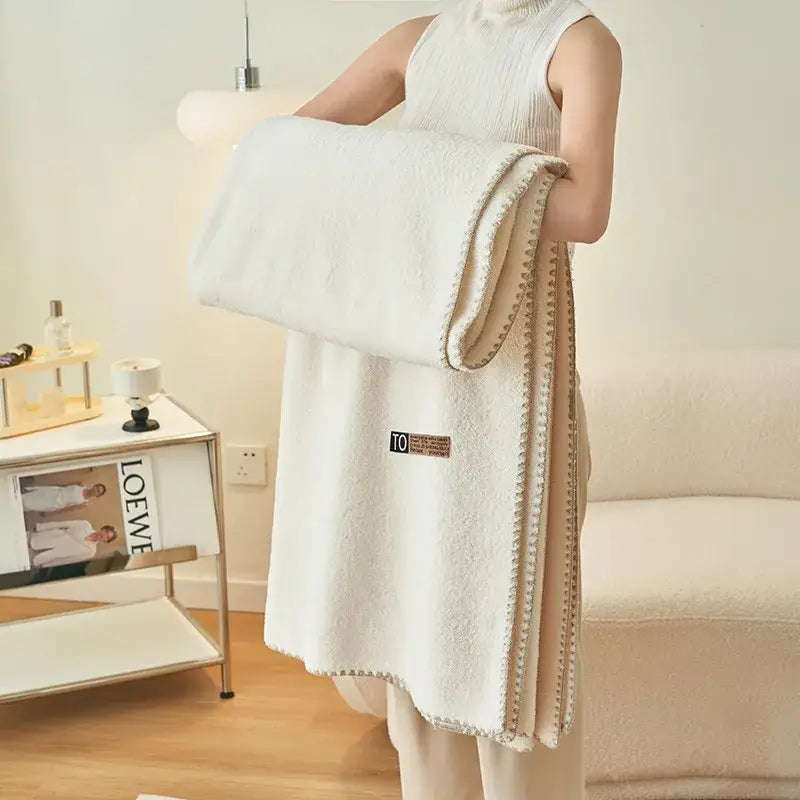 A plush white throw blanket with beige stitching complements the textured mint green decorbites cloud comforter
