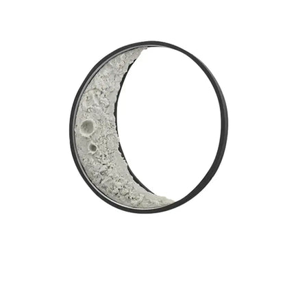 A crescent wall lamp with a textured grayish-white lunar surface and sleek black frame for garden terrace lighting