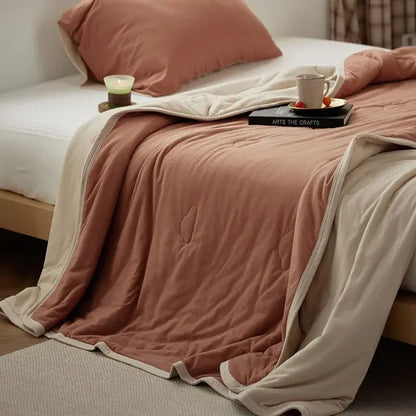A soft two-toned decorbites cotton summer comforter in dusty rose and cream with a plush textured surface