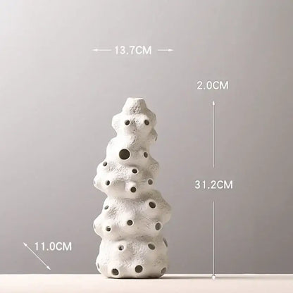 White textured ceramic vase set with stacked organic form and circular holes featuring artificial flowers for living room