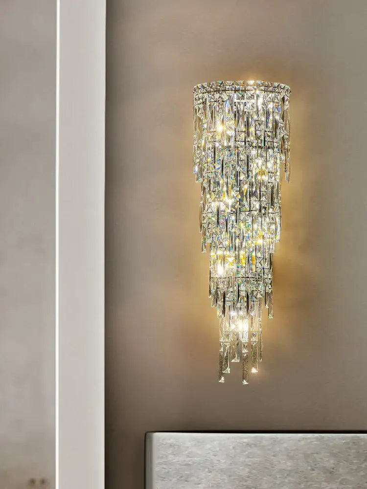 Tiered cascading crystal wall light with faceted glass prisms refracting warm light for luxury decorbites crystal wall decor