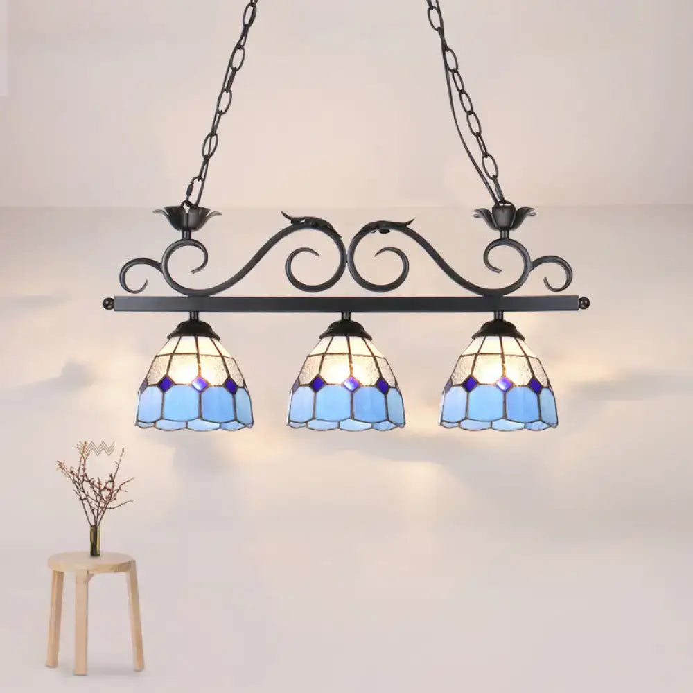 Blue stained glass pendant light fixture with ornate black metal frame and curved bird shape by DecorBites