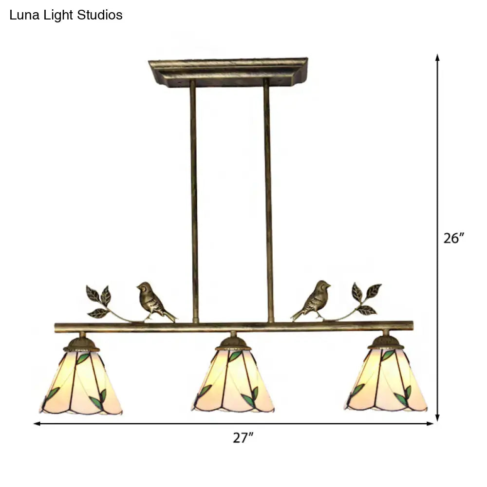 Antique brass-finished DecorBites™ three-light island lighting fixture with stained glass cone shades and green leaf pattern