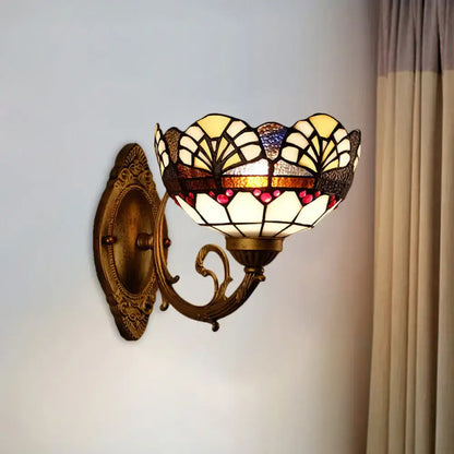Antique brass-finished wall sconce with tiffany gold cut floral stained glass shade in cream amber and deep red hues
