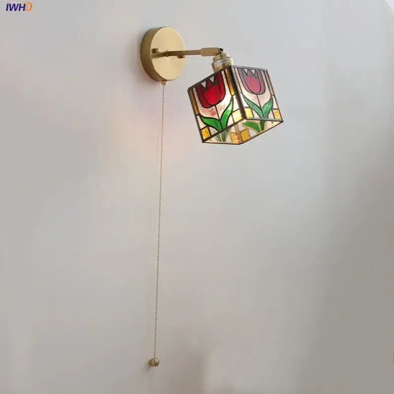 A brass-finished wall light with colorful square glass featuring red tulips and green leaves for bedroom decorbites sconce