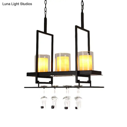 Black metal chandelier with three warm yellow candle-style lights and metal wine glass rack under traditional black marble pendant