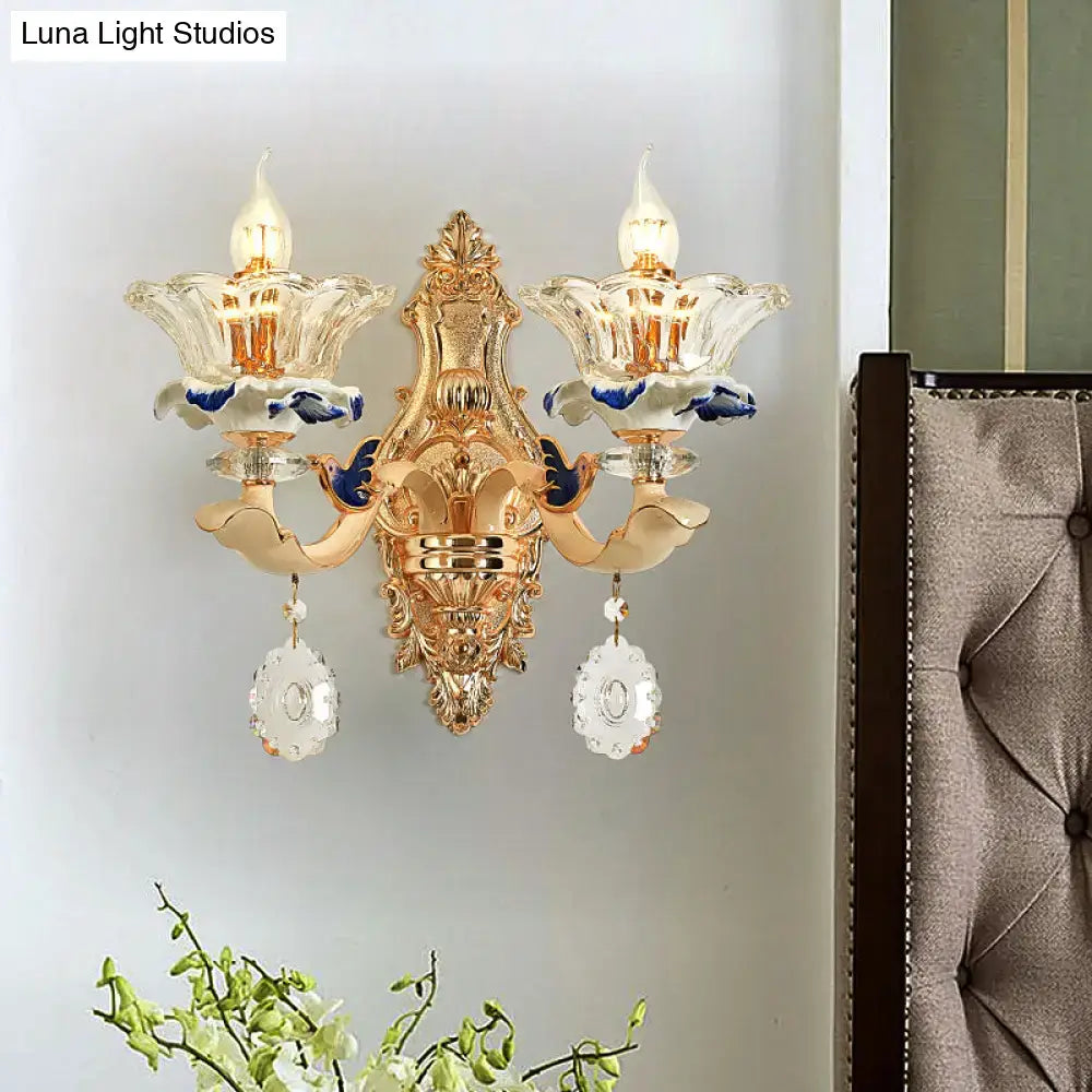 Traditional brass wall sconce light with gold-toned ornate design and crystal flower shades for living room use