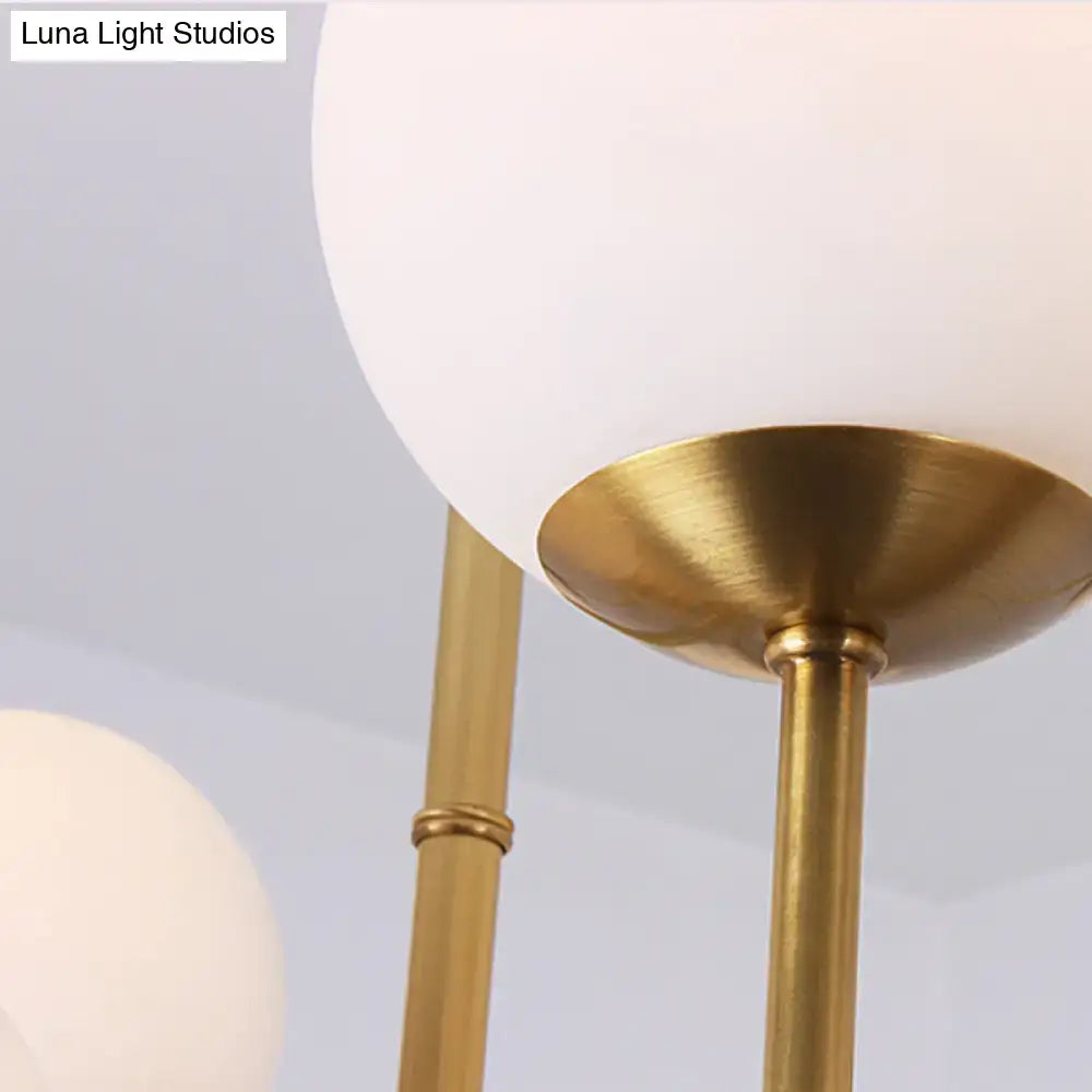 A DecorBites opal glass island pendant light with brushed brass finish and large white spherical shades for dining room