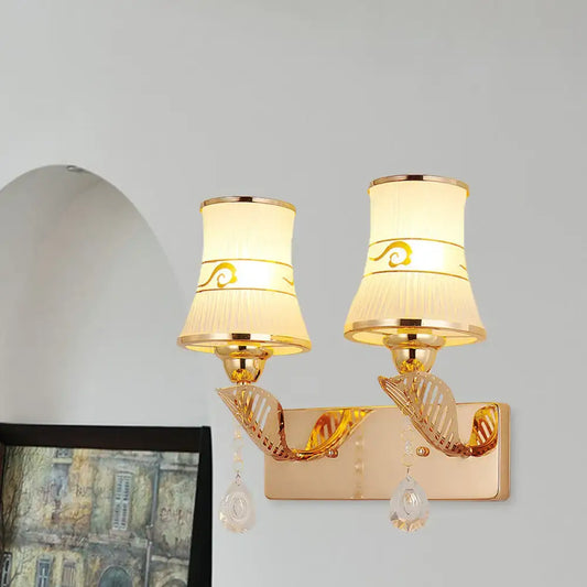Traditional gold and cream wall sconce light with fabric shades, gold swirls, and crystal teardrop pendants for dining room