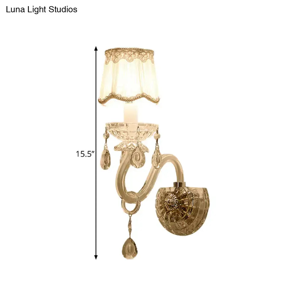 Traditional gold crystal candle wall lamp with ornate curved arm and lace trimmed cream shade for bedroom use