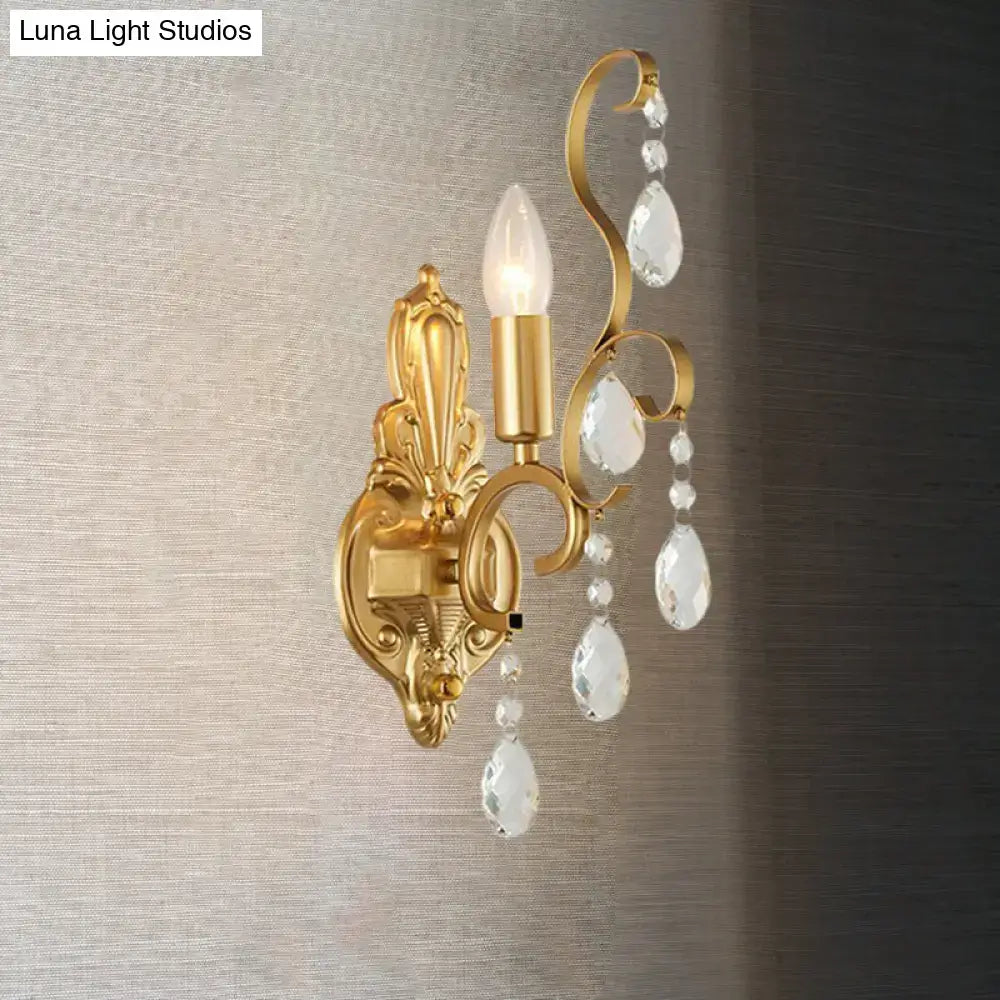 Traditional gold metal candle wall lamp with ornate design and dangling crystal teardrop pendants for living room use