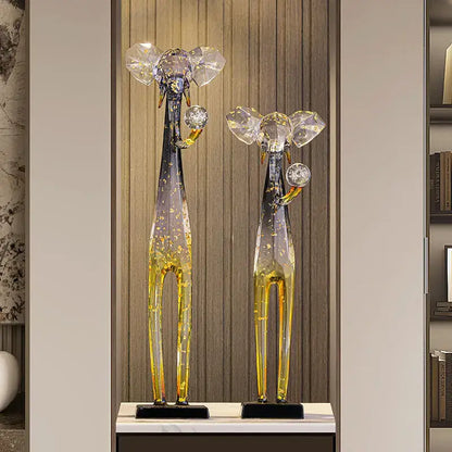 Two tall glass giraffe sculptures with translucent blue and amber bodies and golden speckles for floor decoration sculpture