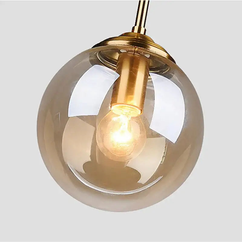 A warm-toned glass pendant light with brass fixture and exposed filament bulb in polished steel for dining room