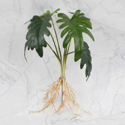 Artificial green monstera plant with glossy leaves and tan roots in tropical plant wall set for living room decor