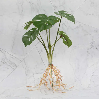 A vibrant green artificial monstera plant with glossy perforated leaves and detailed roots for a plant wall set