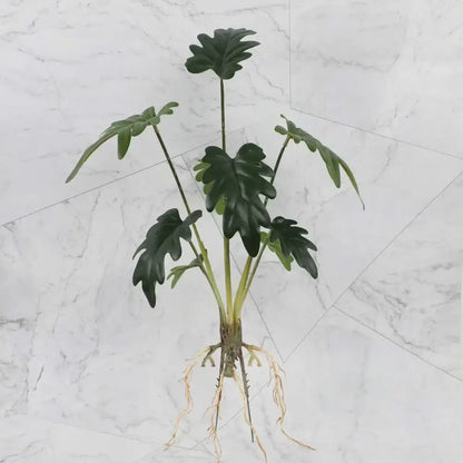 Artificial green leafy plant with glossy leaves and visible roots in a tropical plant wall set for living room decor