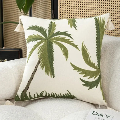 White cushion cover with embroidered green palm trees and cream tassels in tropical olive and cream patchwork design