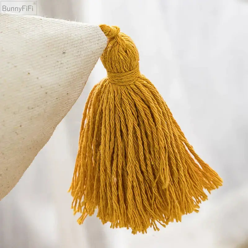 A mustard-yellow tufted tassel made of twisted yarn on a cushion cover for decorbites boho style living room decor