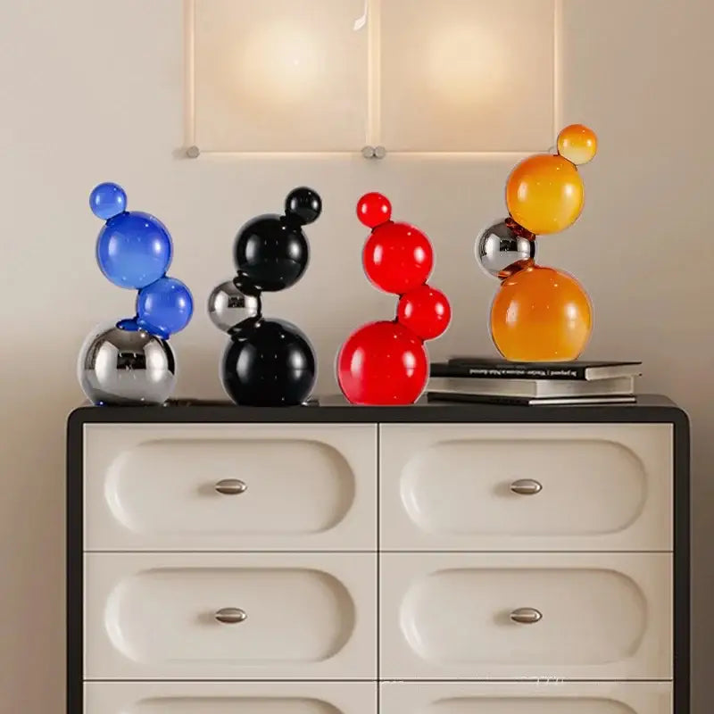 Set of four modern crystal bubble decor spheres in blue black red and orange with reflective metallic bases for home decor