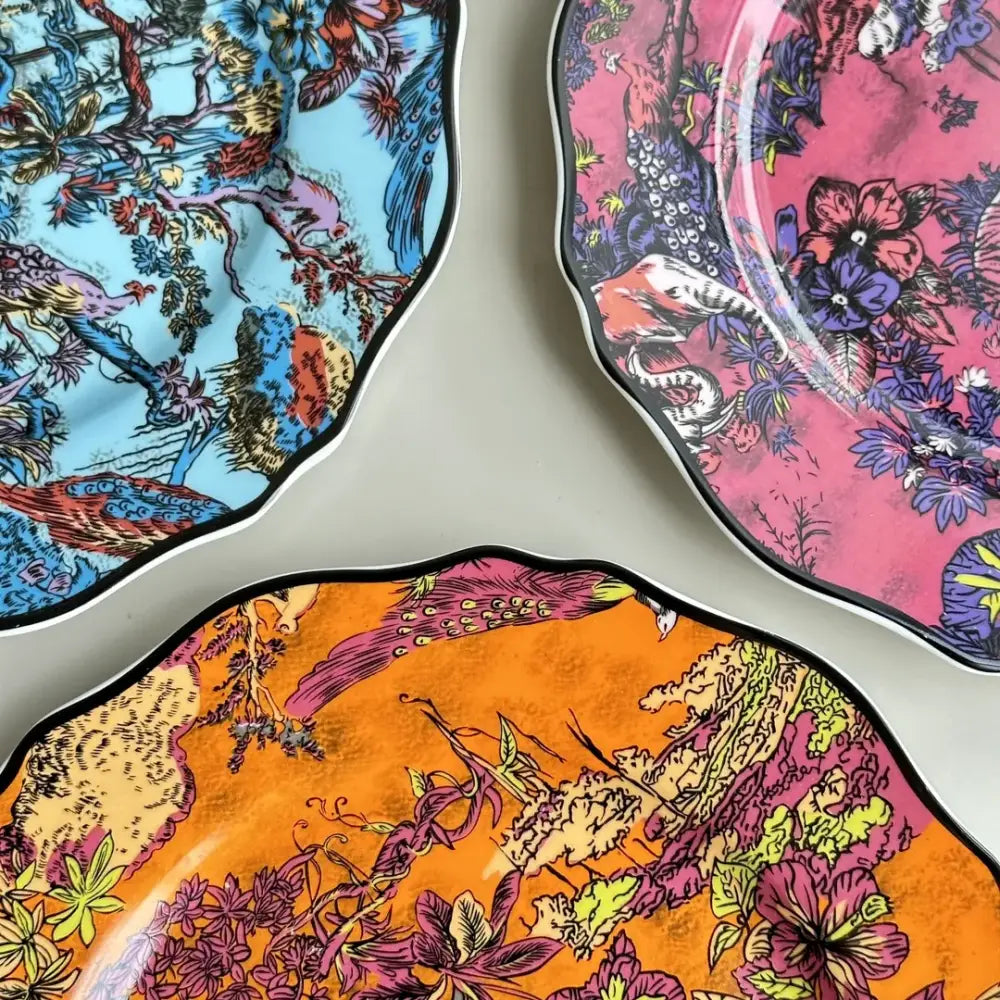 Vibrant jungle flower bone dining plates set with scalloped edges and bold turquoise pink orange purple floral bird motifs