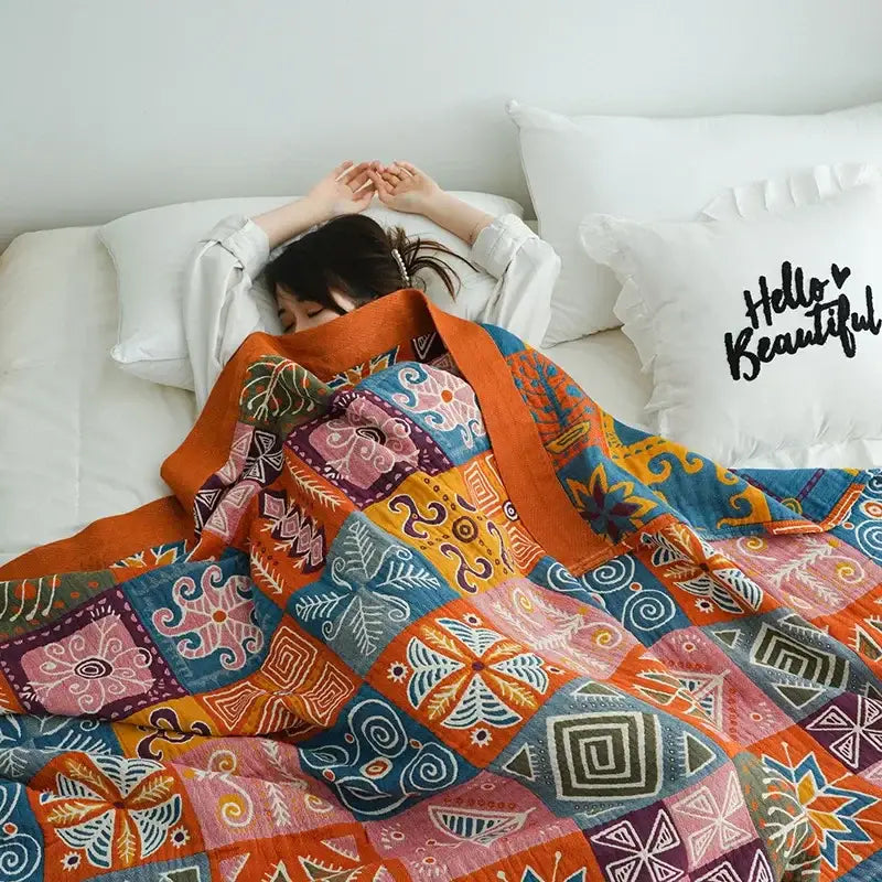 Vibrant orange and gold geometric nordic throw blanket with bold floral patchwork in blue pink and purple hues
