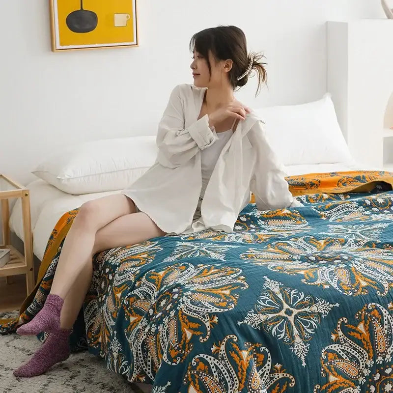 Teal and gold paisley patterned quilt throw blanket complementing a vibrant orange and gold geometric nordic throw blanket design