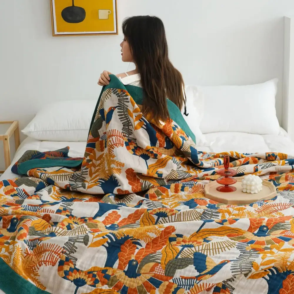 Cozy nordic throw blanket with vibrant orange blue and teal botanical print on white background for bedroom use