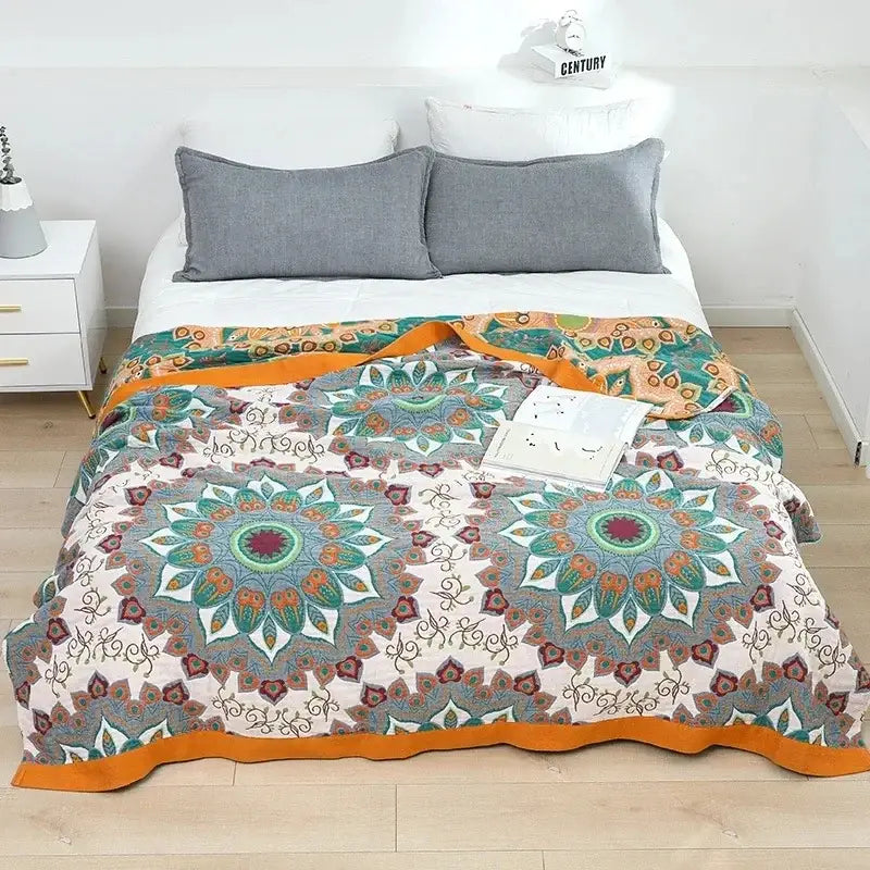 A cozy nordic throw blanket with intricate teal orange cream mandala patterns and a vibrant orange border