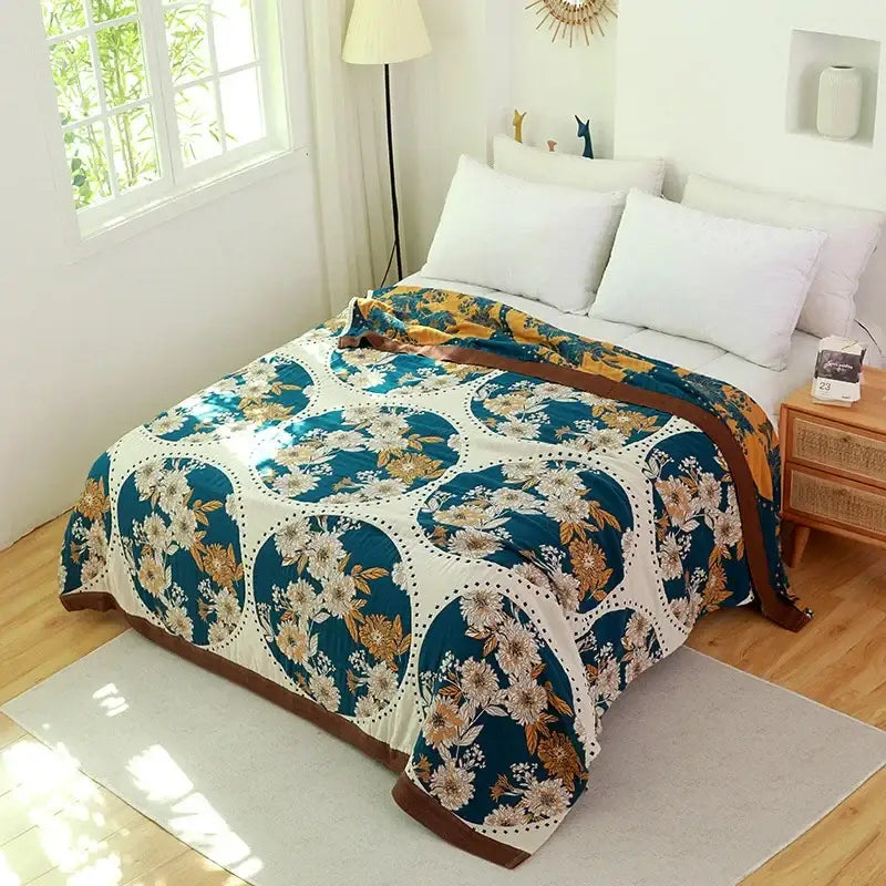 Cozy teal and cream floral throw blanket with circular patterns and brown trim beside vibrant orange and gold nordic throw blanket