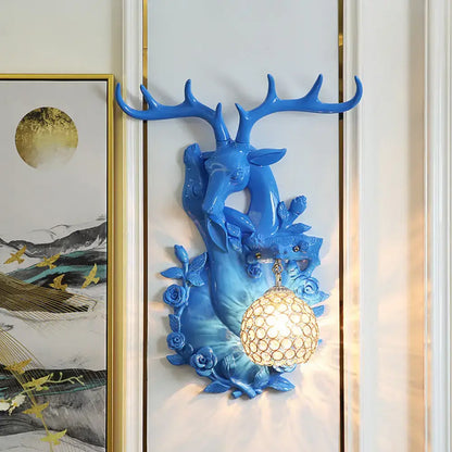 Vibrant blue deer head accent wall sconce with ornate antlers floral detailing and glowing crystal globe lampshade
