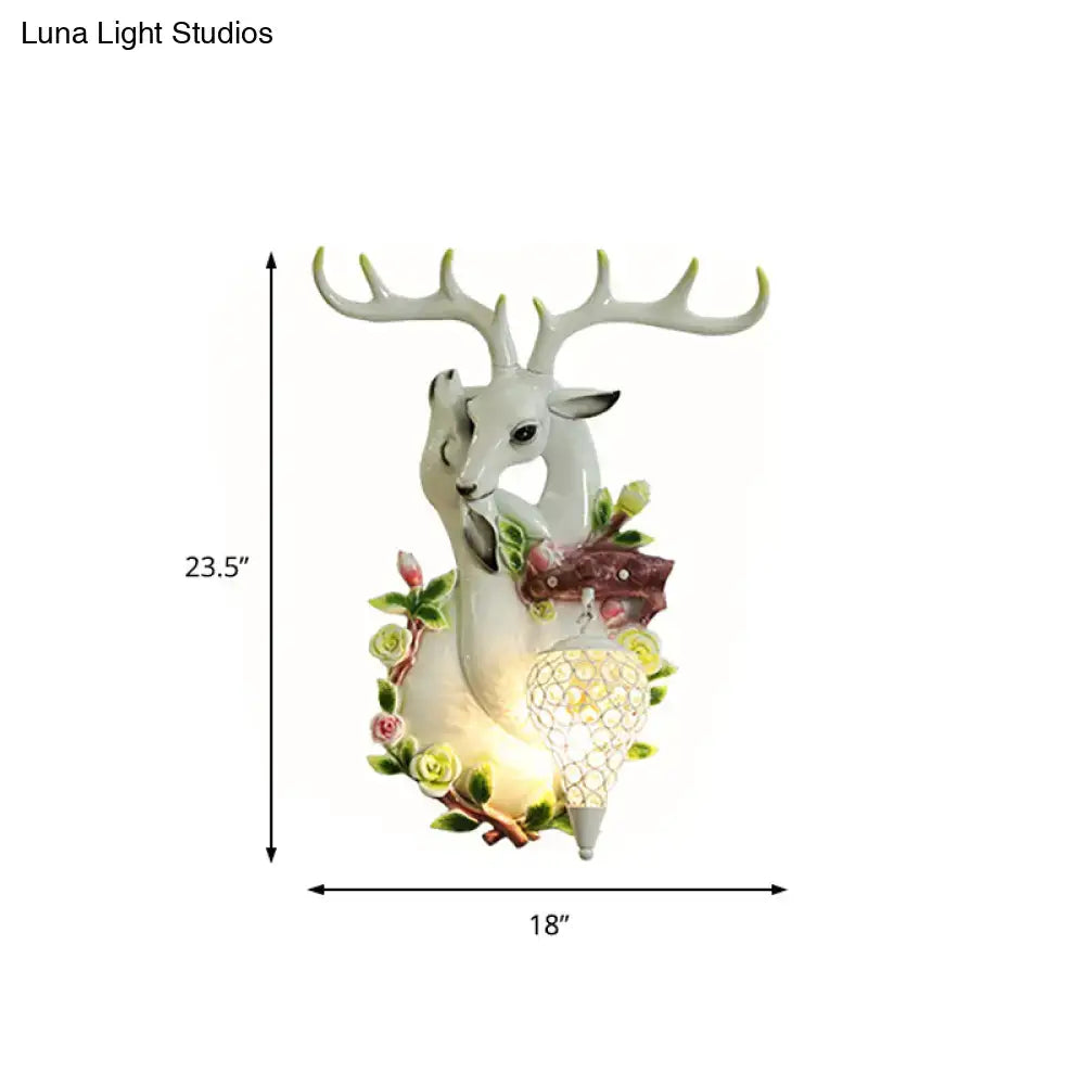 White deer head accent figurine with antlers and yellow floral details featuring a glowing crystal sconce light
