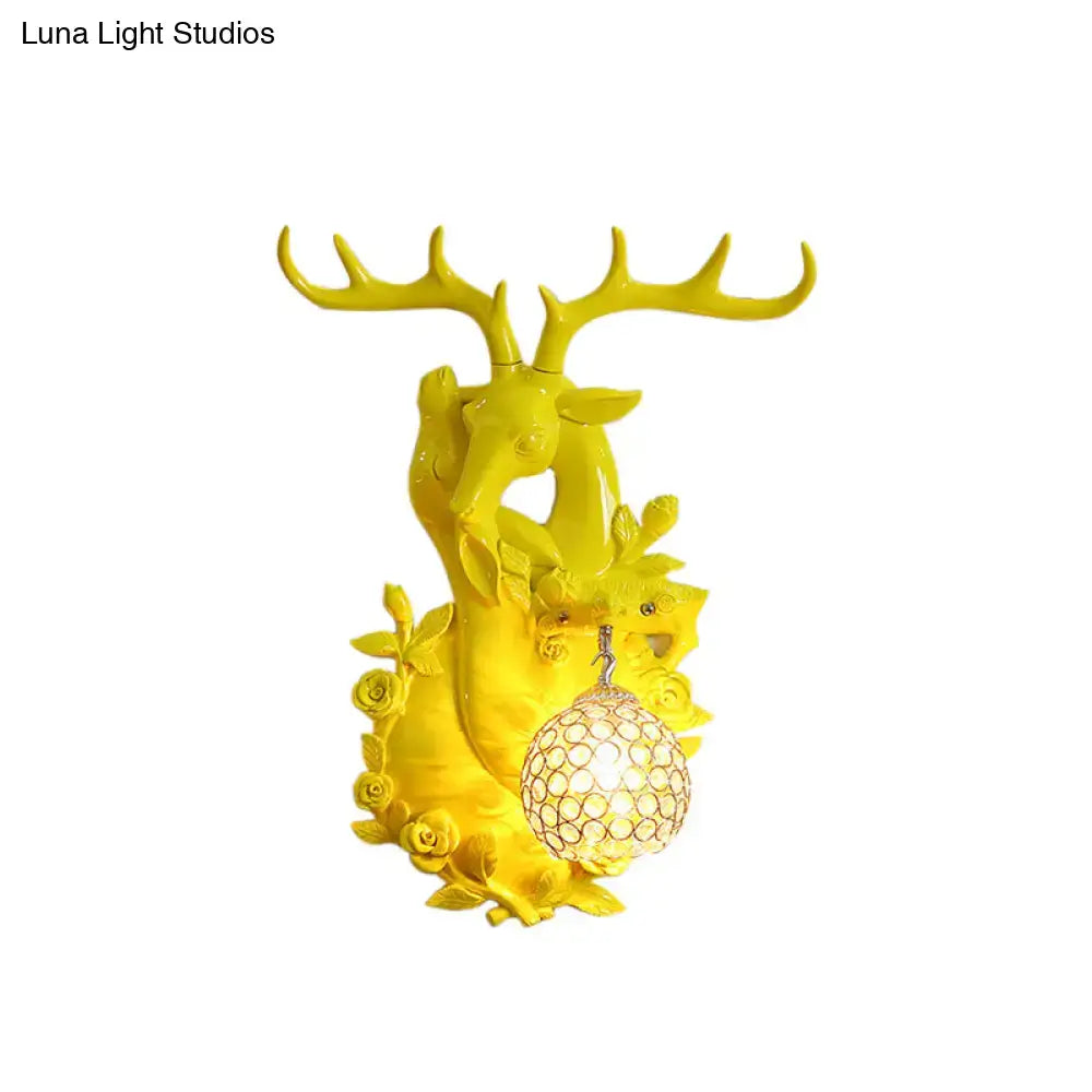 Vibrant yellow deer head accent wall sconce with ornate antlers floral details and crystal-encrusted spherical light fixture