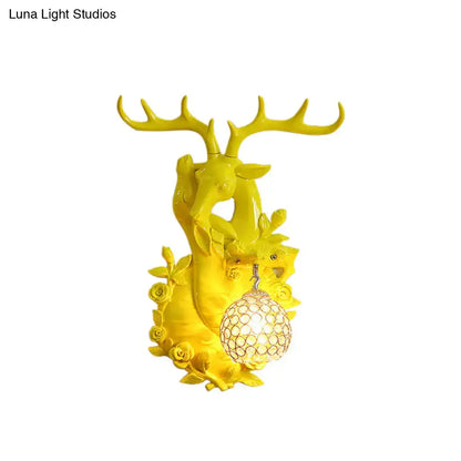 Vibrant yellow deer head accent wall sconce with ornate antlers floral details and crystal-encrusted spherical light fixture